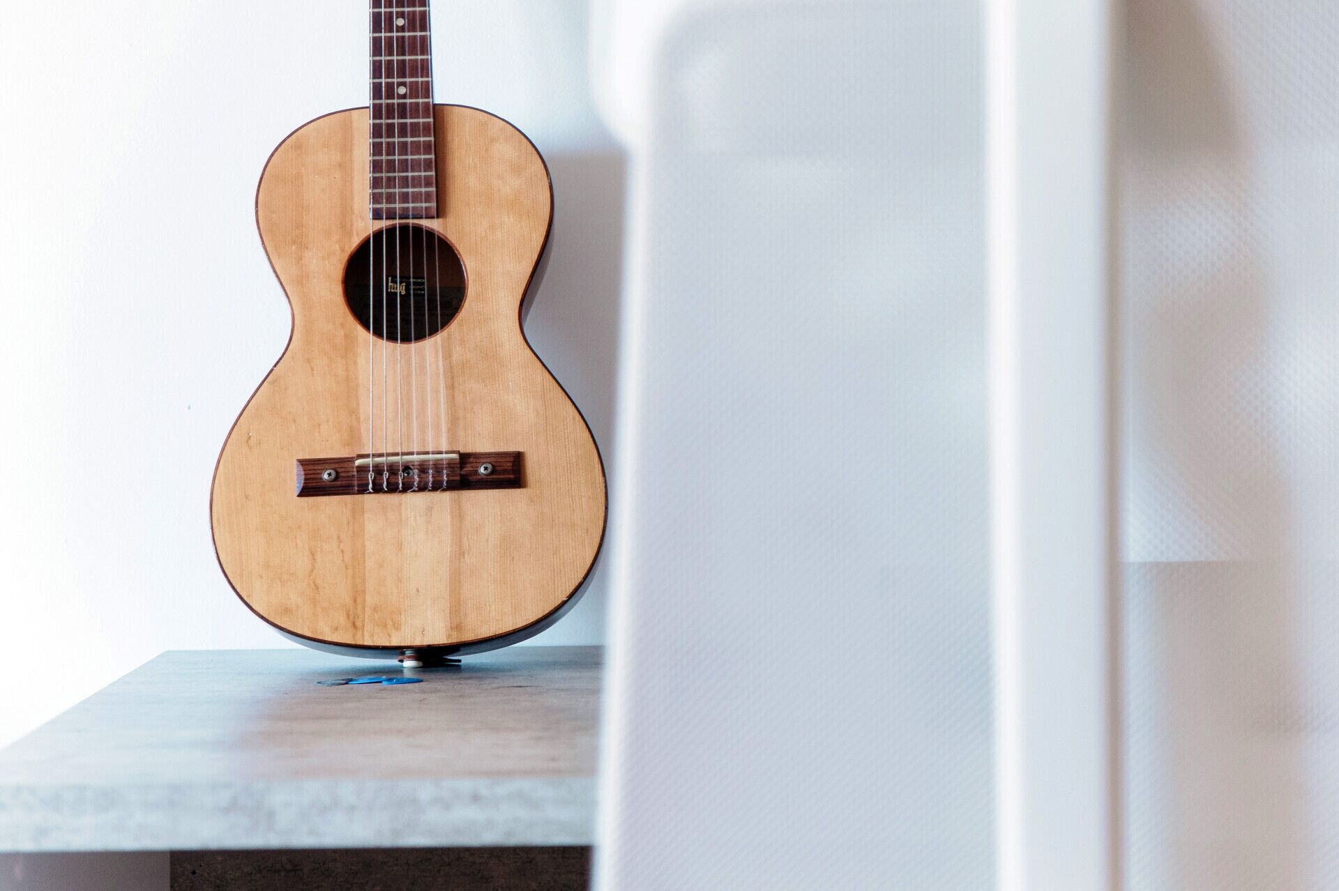 Una guitarra acústica de madera sobre una superficie clara.