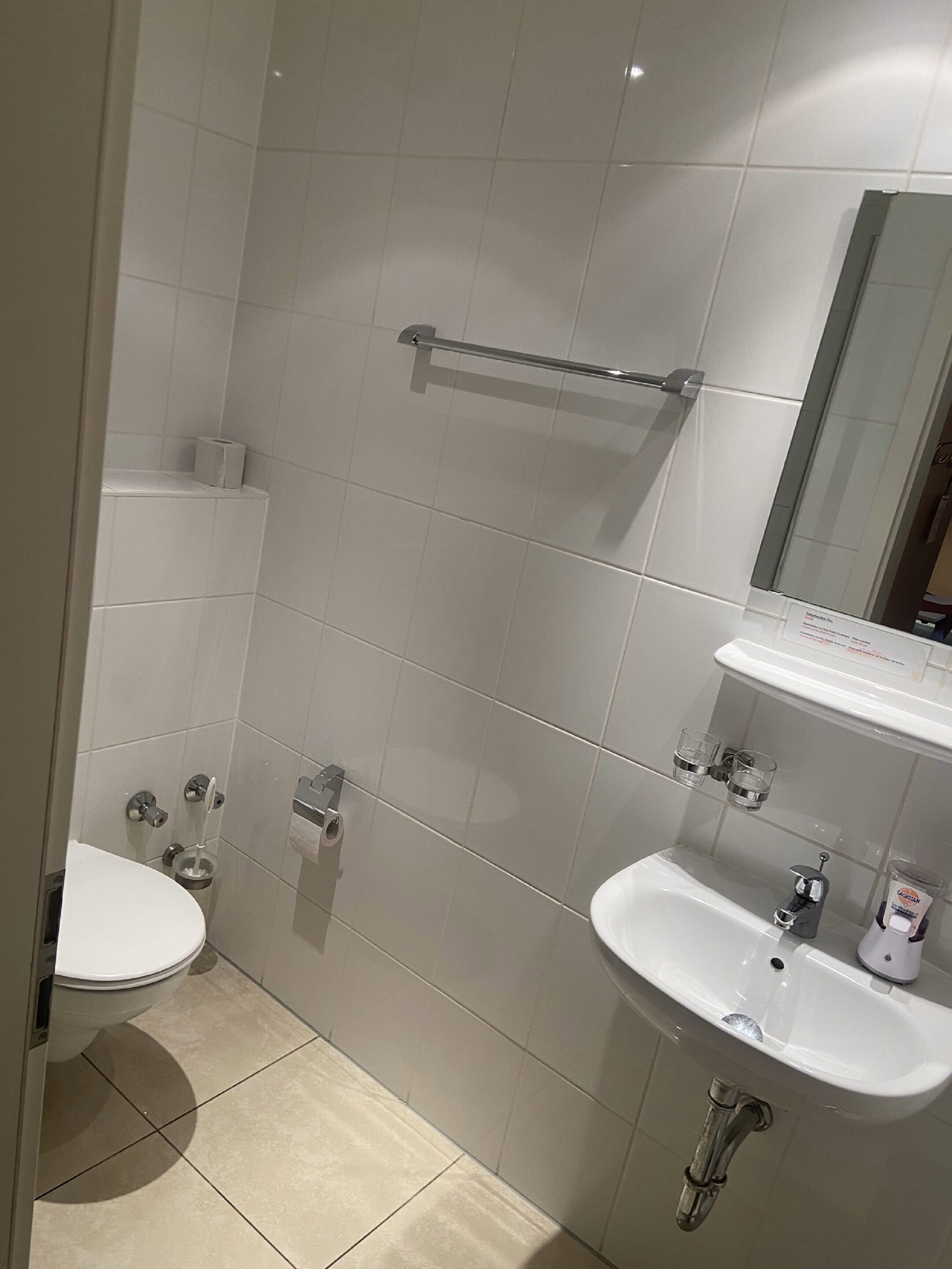 A bathroom with a toilet, sink, and mirror.