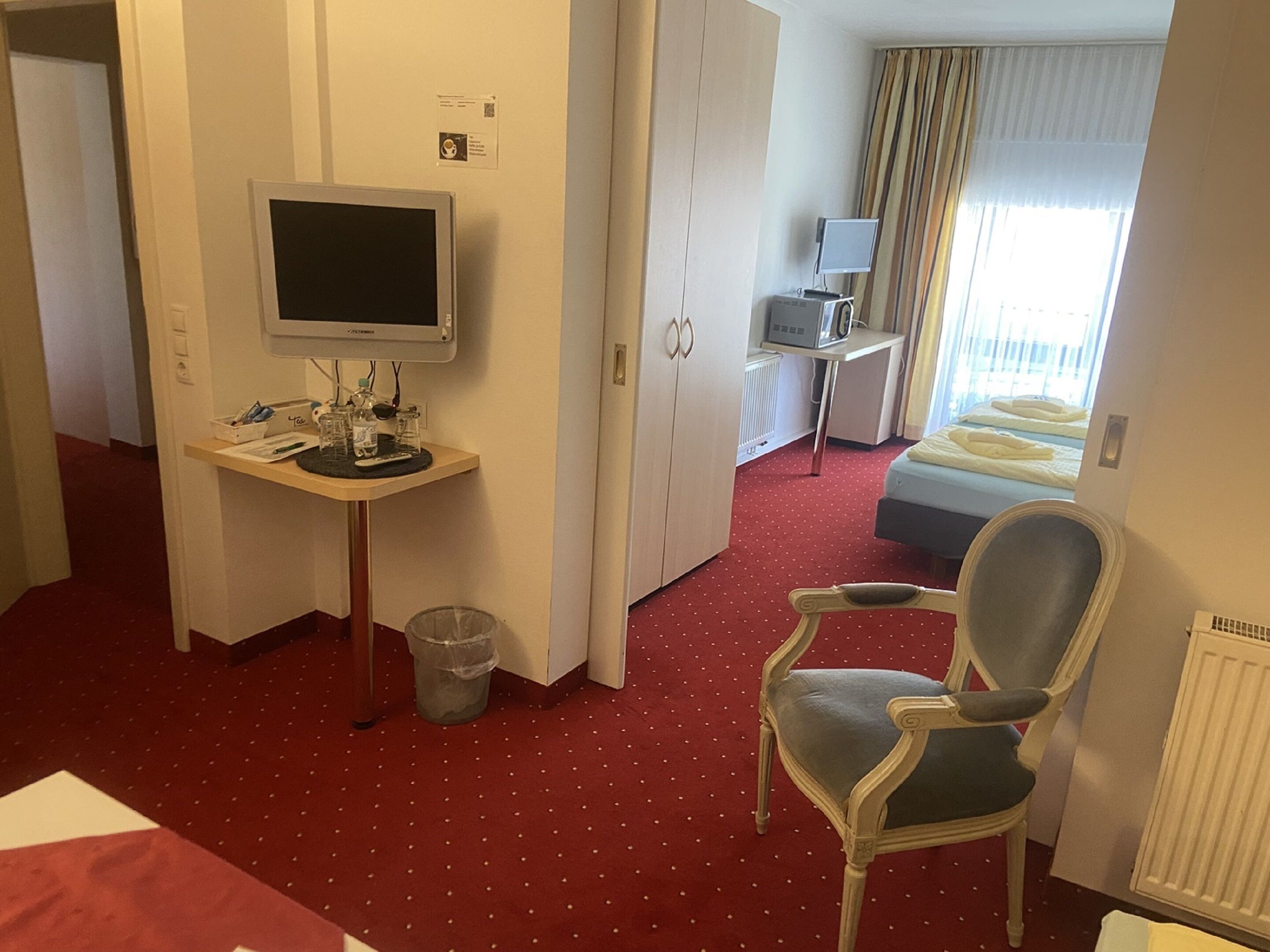 Une chambre d’hôtel comprenant un lit, un bureau avec un ordinateur, une chaise et un téléviseur.
