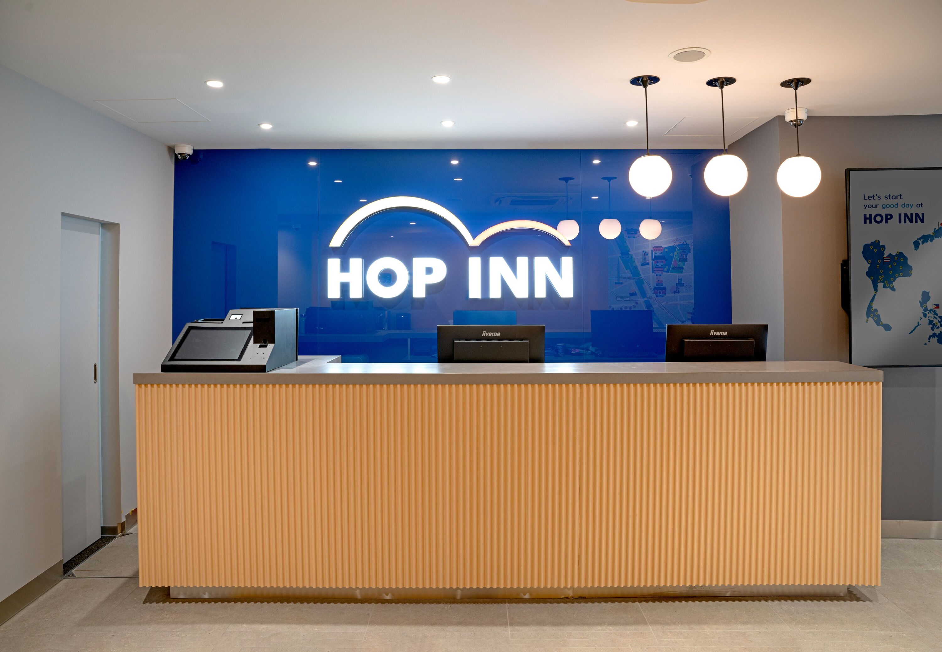 A reception desk with a blue wall and the text "HOP INN" in white letters.