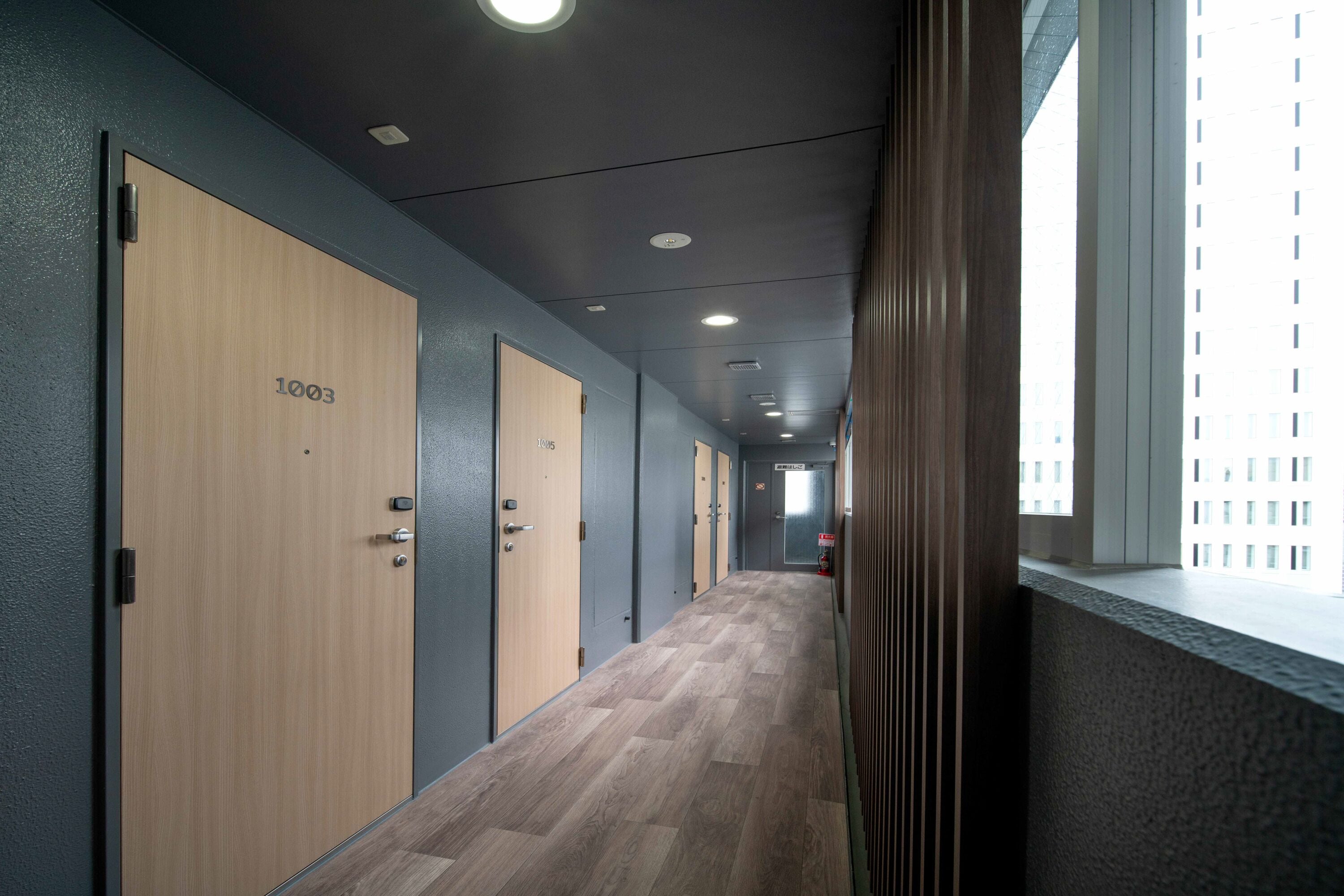 A hallway with wooden doors, numbered 1003, leading to individual rooms.