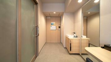 Um corredor com porta de madeira, pia e espelho.