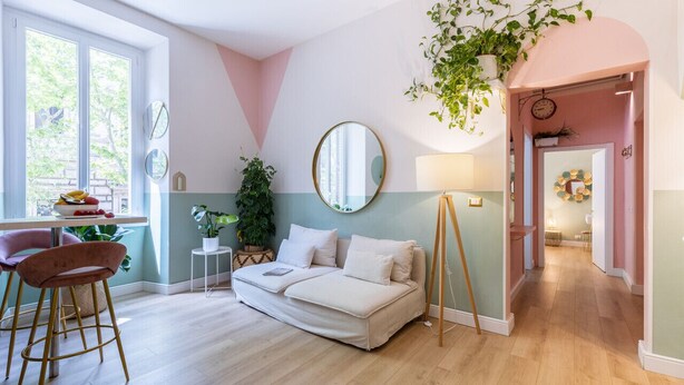Una sala de estar moderna con un sofá, una zona de comedor con mesa y sillas, y un ventanal con vistas a zonas verdes.