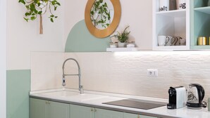 Una cocina con un lavamanos blanco, una cafetera y una repisa con recipientes de sal y azúcar.