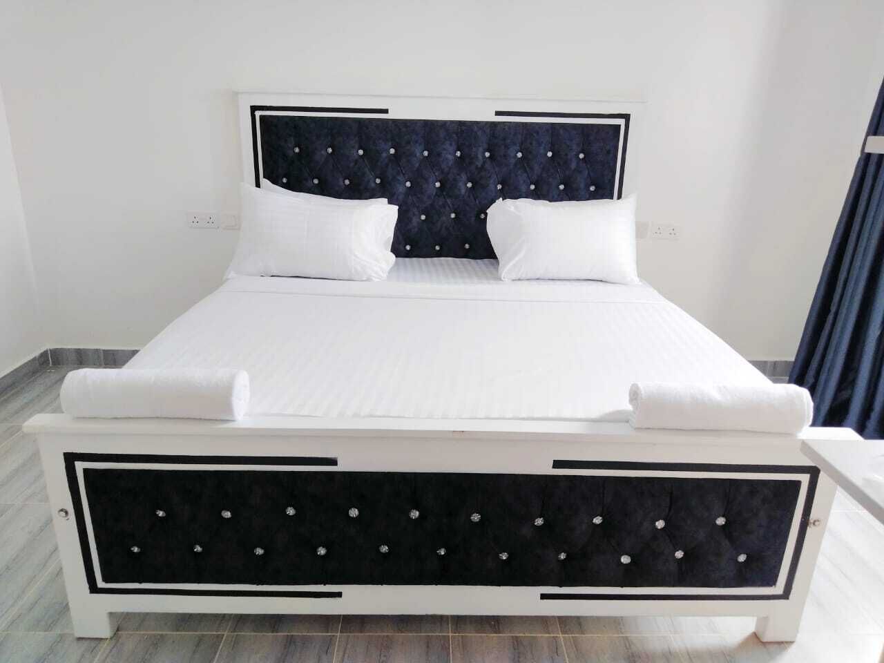 A bed with a tufted headboard, white bedding, and a black and white frame.