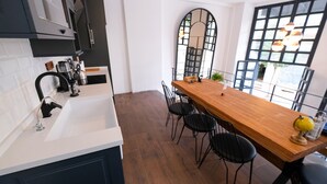 A modern kitchen with a wooden dining table and chairs, a large window with a view, and a black and white color scheme. - Hostel Le Banc (Istanbul)