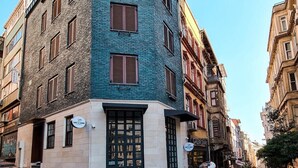 A narrow street with a corner building featuring a cafe and a shop. - Hostel Le Banc (Istanbul)