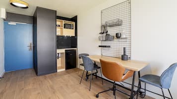A compact kitchen with a microwave, sink, and cabinets. There is a dining area with a table and chairs.