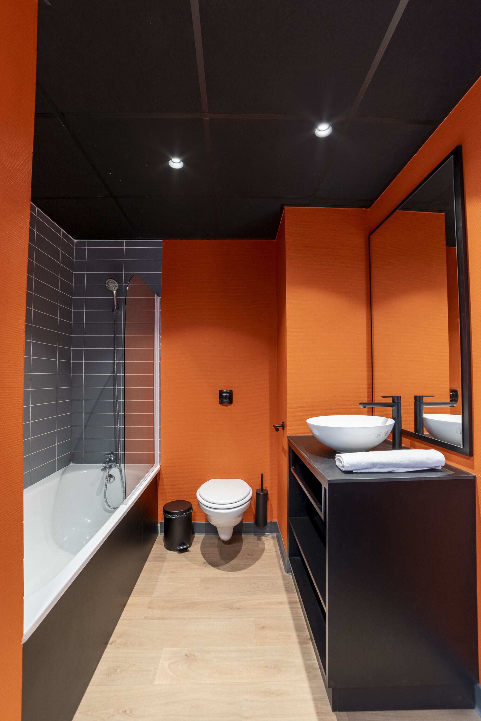 A modern bathroom with a bathtub, toilet, and large mirror.