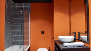 A modern bathroom with a bathtub, toilet, and large mirror.