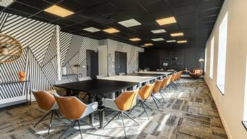 A conference room with a long table, multiple chairs, patterned walls, and a carpeted floor.