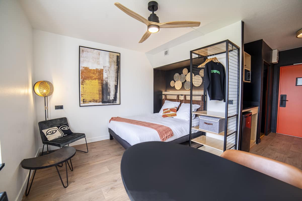 Une chambre à coucher moderne avec un lit, une chaise, un bureau et une armoire.