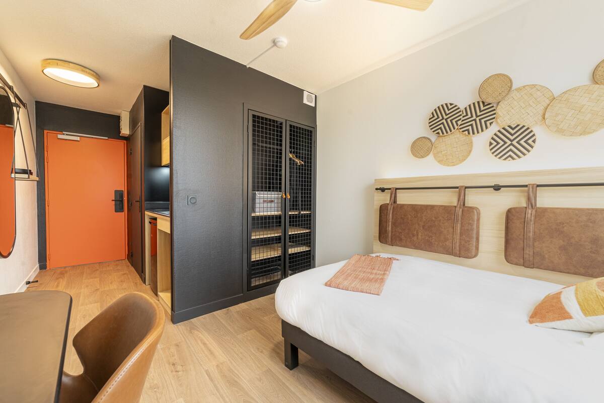 Une chambre d’hôtel moderne équipée d’un lit, d’un bureau et d’une armoire.
