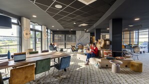 A modern office space with a long table, chairs, and a seating area with cushions. - Cowool Toulouse (Toulouse)