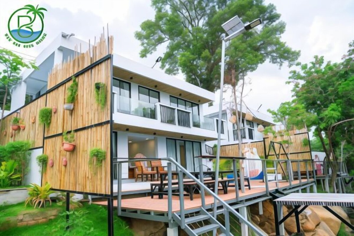 A modern building with a wooden facade, outdoor seating, and a solar panel.