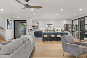 A modern kitchen with white cabinets, stainless steel appliances, and a central island with bar stools. - Valley View: Chic Design w/ Pool, Grille, Firepit (Scottsdale)