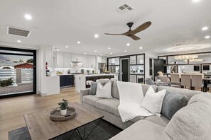 A modern living room with a sofa, a coffee table with a plant, and a ceiling fan.