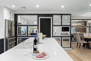 A modern kitchen with a central island, built-in appliances, and a dining area with a chandelier. - Valley View: Chic Design w/ Pool, Grille, Firepit (Scottsdale)