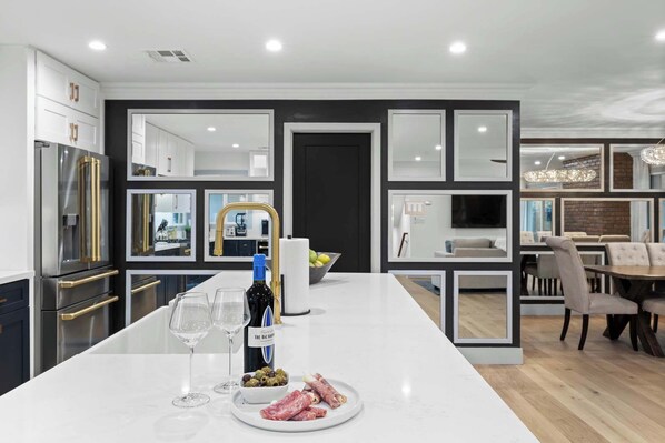 A modern kitchen with a central island, built-in appliances, and a dining area with a chandelier.