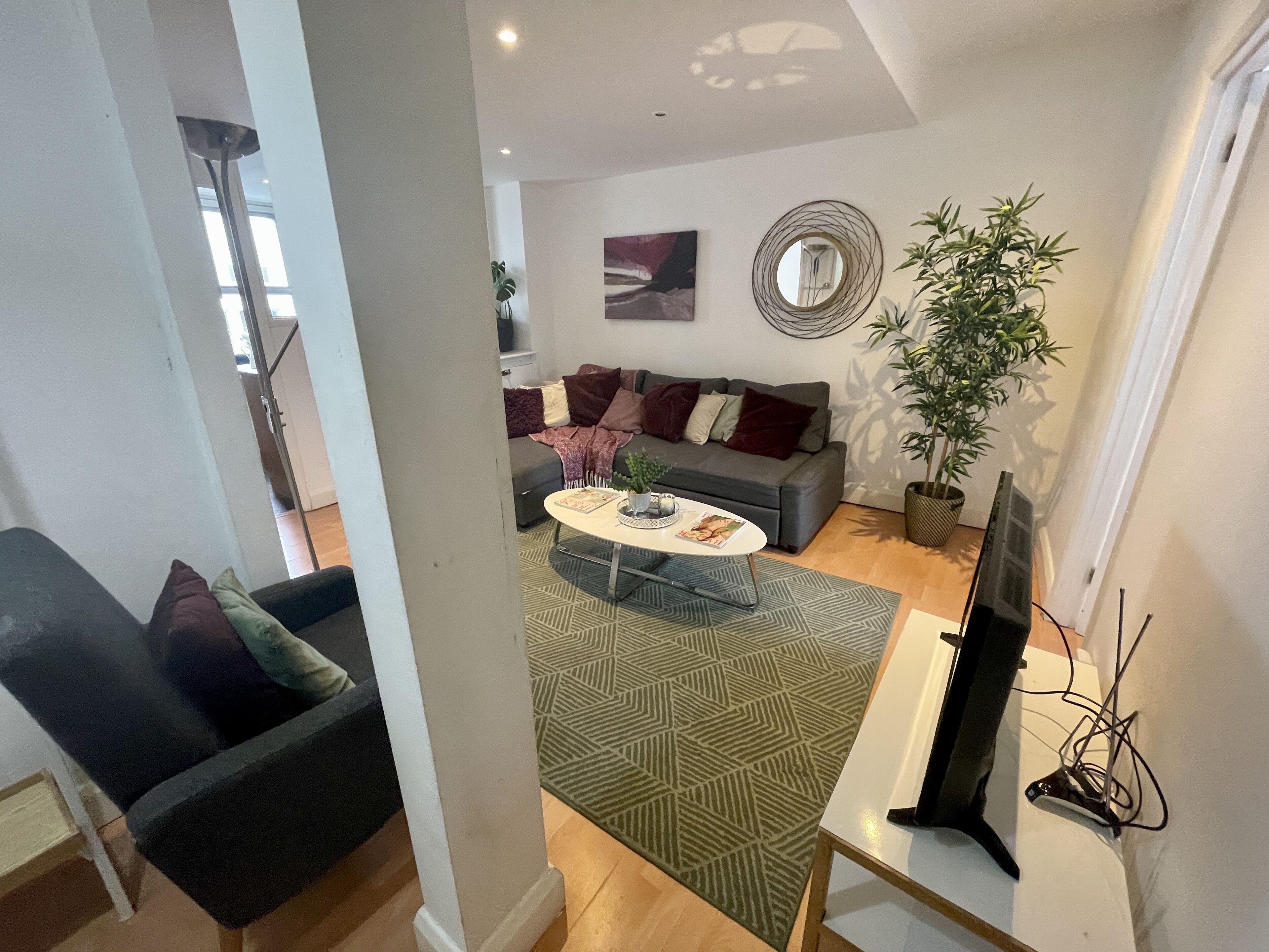 A modern living room with a grey sofa, a round coffee table, and a potted plant.