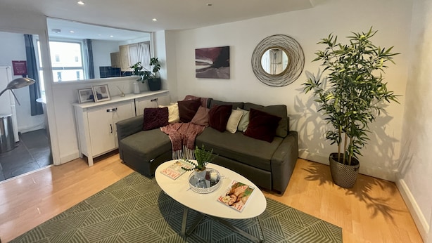 A modern living room with a sofa, coffee table, and potted plants. - Cosy two bedroom flat Fulham Broadway (London)