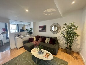 A modern living room with a sofa, coffee table, and potted plants. - Cosy two bedroom flat Fulham Broadway (London)