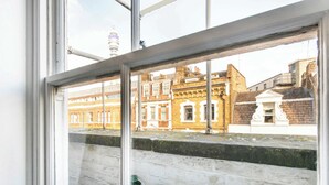 Una ventana con vistas a un paisaje urbano, incluyendo edificios y una torre.