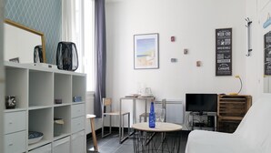 A hotel room with a bed, a desk with a chair, a TV, and a shelf with decorative items. - Seafront studio close to all amenities (Les Sables-d´Olonne)