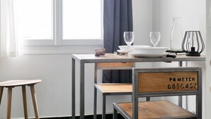 A modern dining area with a table set for two, a chair, a small candle, and a decorative lamp. - Seafront studio close to all amenities (Les Sables-d´Olonne)