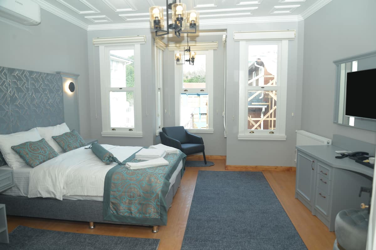 A bedroom with a bed, a desk, a chair, and a TV.