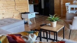 A cozy living room with a flat-screen TV, a black refrigerator, a dining table with chairs, and a sofa. - Lazar House Ada Bojana (Ulcinj)