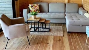A cozy wooden interior with a grey sofa, a small table with a plant, and a chair. - Lazar House Ada Bojana (Ulcinj)