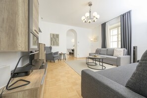 A modern living room with a grey sofa, a coffee table, and a TV on a wooden desk.