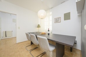 A dining area with a table, chairs, a lamp, and a bottle of wine.