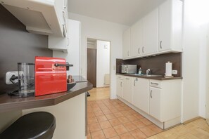 A kitchen with white cabinets, a red espresso machine, a microwave, and a coffee maker.