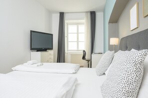 A hotel room with a bed, a television, a desk, and a chair.
