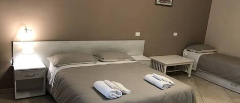 A hotel room with a large bed, a bedside table, a nightstand, and a small table with a chair.
