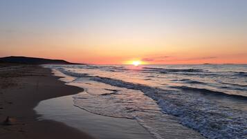 Praia particular, areia branca, espreguiçadeiras, guarda-sóis