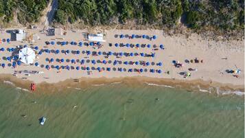 Aan een privéstrand, wit zand, ligstoelen, parasols