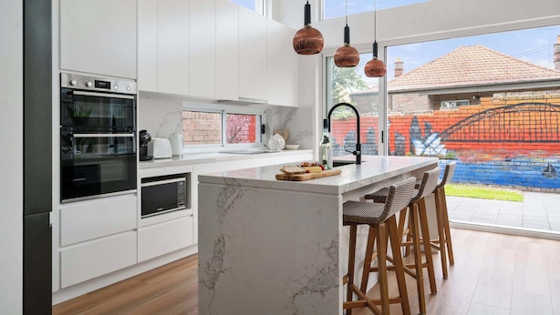 A modern kitchen with white cabinetry, a marble island, and a large window overlooking a colorful outdoor area. - Rozelle Retreat by the Bay Run (Rozelle)
