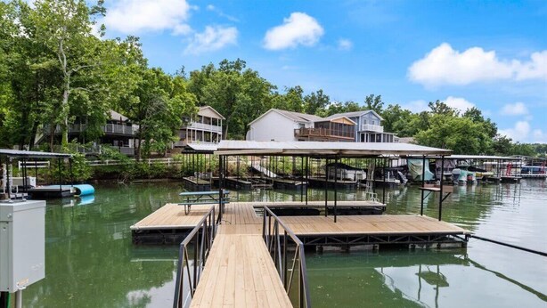 A waterfront property with multiple docked boats, a wooden pier, and several houses with attached docks. - Lakefront House Next to Camden On The Lake (Lake Ozark)