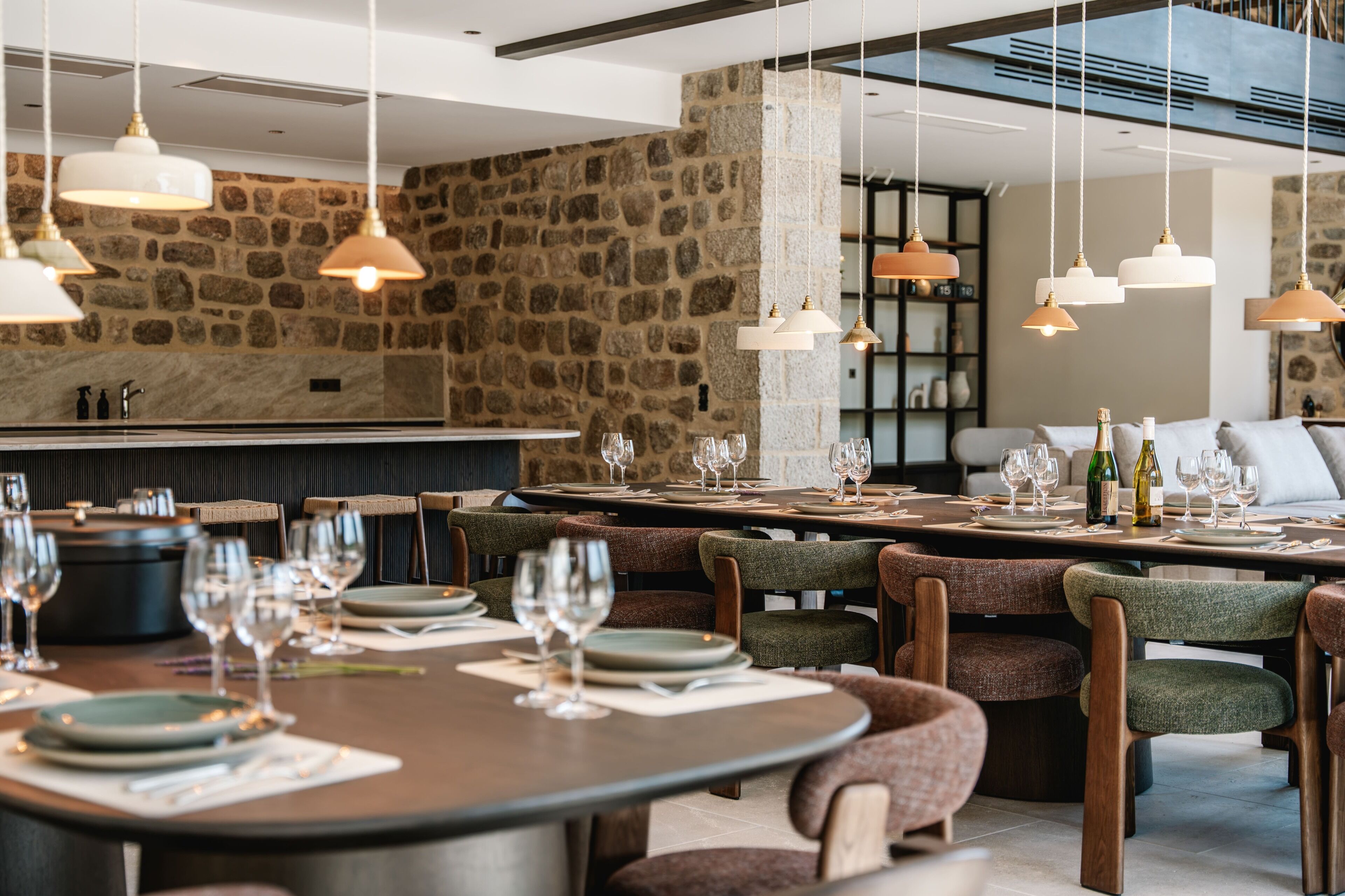 Un restaurante con paredes de piedra, varias mesas para comer y lámparas colgantes.