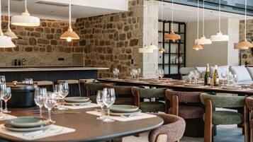 Un restaurante con paredes de piedra, varias mesas para comer y lámparas colgantes.