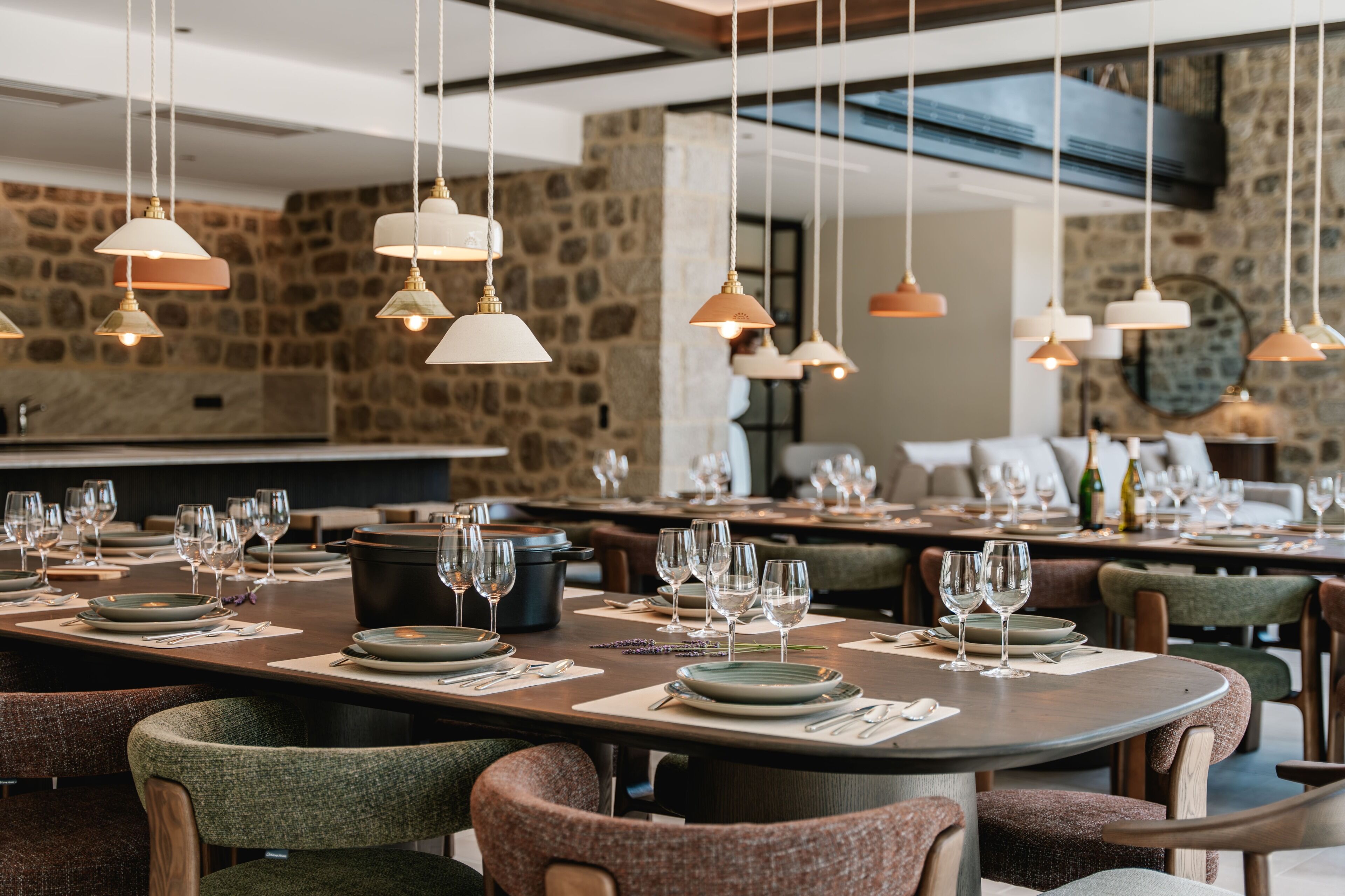 Een restaurant met meerdere eettafels gedekt voor gasten, elk met borden, bestek en wijnglazen.