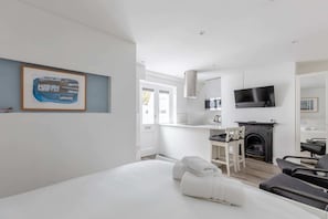A modern hotel room with a bed, a TV, a fireplace, and a dining area.