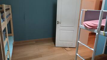 Una habitación con una cama litera, una puerta y suelo de madera.