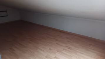 Quarto com soalho de madeira e paredes brancas.