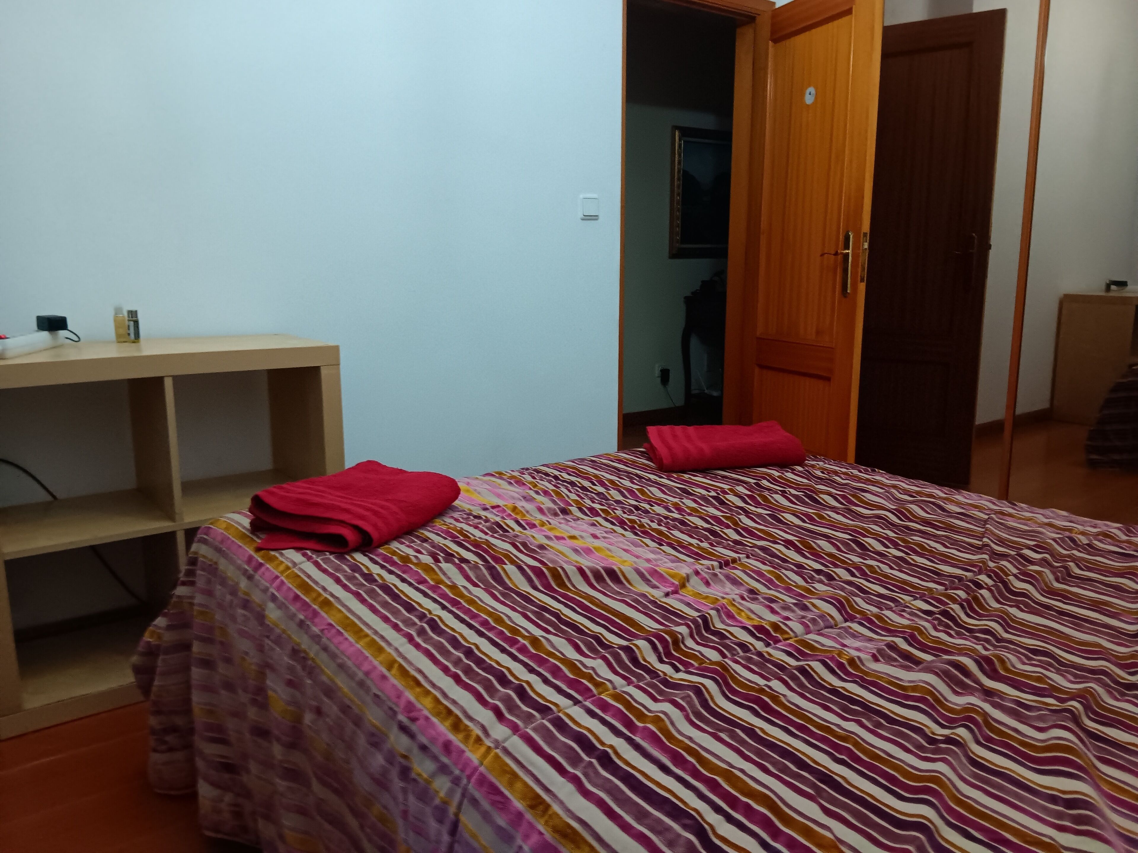 Una habitación con una cama, un escritorio de madera y un armario.