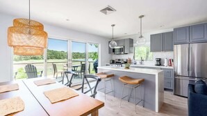 Une cuisine moderne dotée d’un grand îlot central, de tabourets de bar et offrant une vue sur l’extérieur.