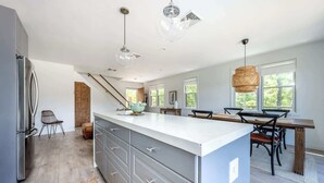 Une cuisine moderne dotée d’un grand îlot central, d’un plancher en bois et d’un coin repas avec une table et des chaises.